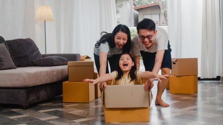 Happy Asian young family having fun laughing moving into new hom