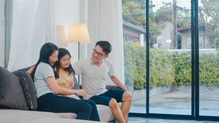 Happy young Asian family play together on couch at home. Chinese